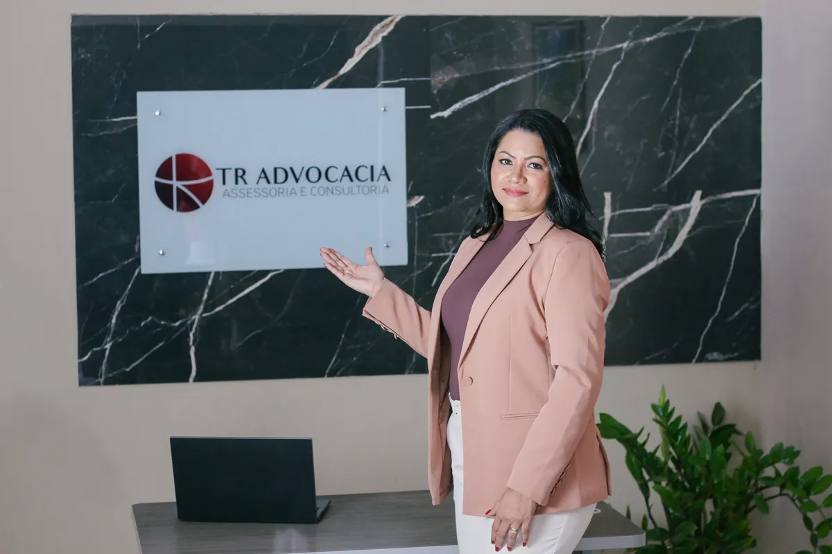 Torlene Rodrigues ao lado da placa da TR Advocacia, no escritório em Matinha/MA